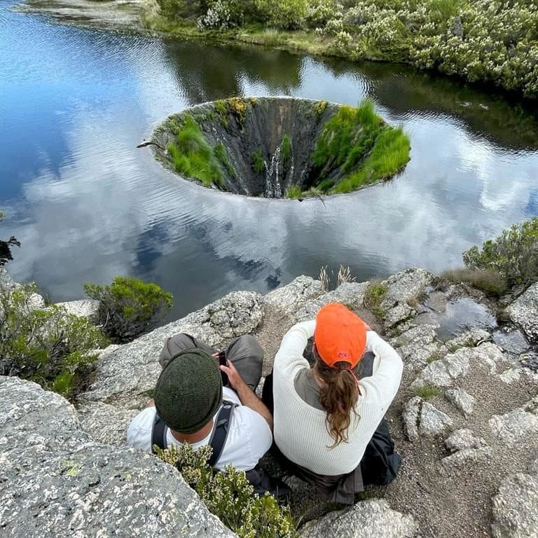 Dois visitantes sobre o funil de pedra do Covão dos Conchos, onde a ribeira se escoa por baixo da montanha