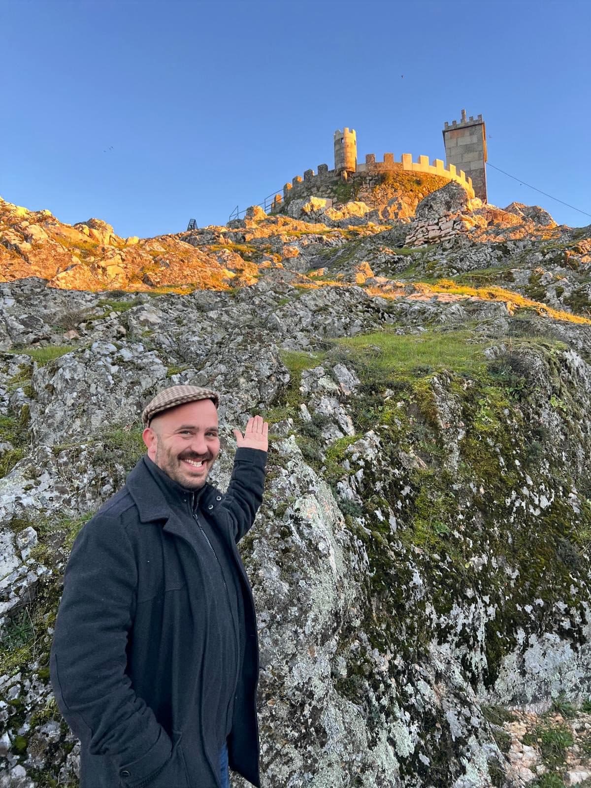 O Gonzi a acenar, com um castelo ao cimo do monte a apanhar a última luz