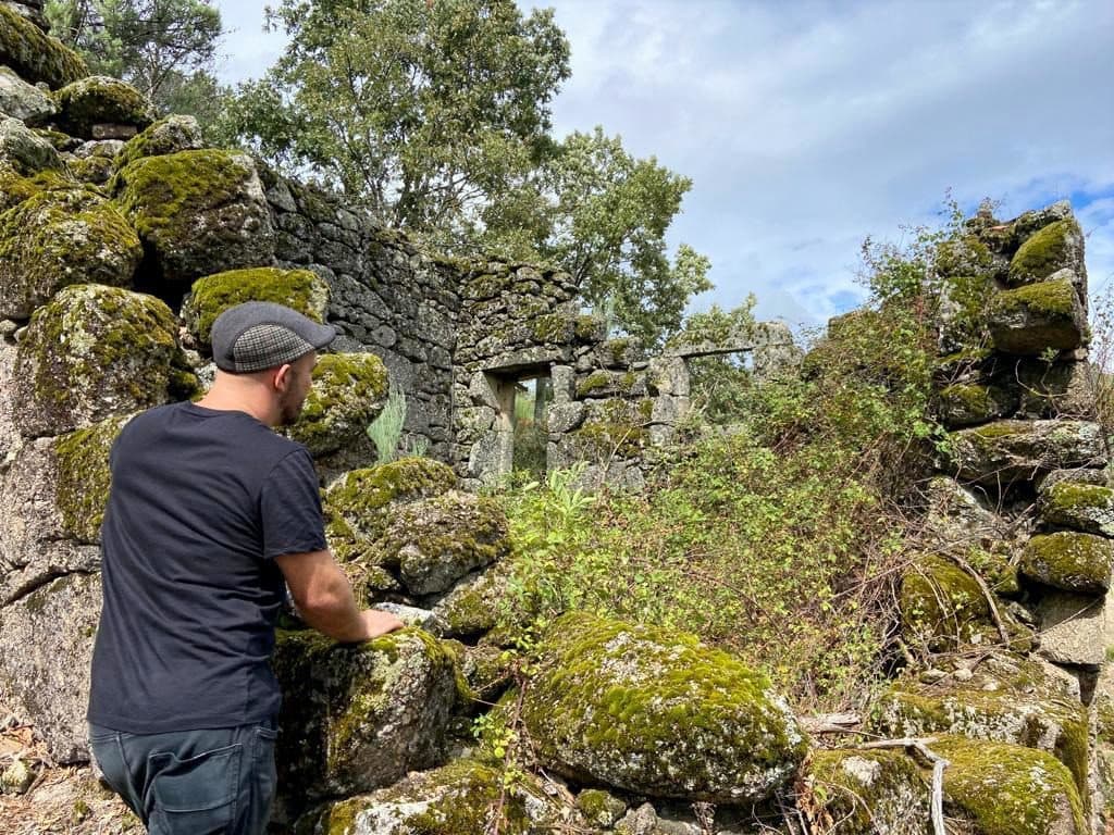 O Gonzi a olhar para as ruínas cobertas de musgo de uma casa de granito